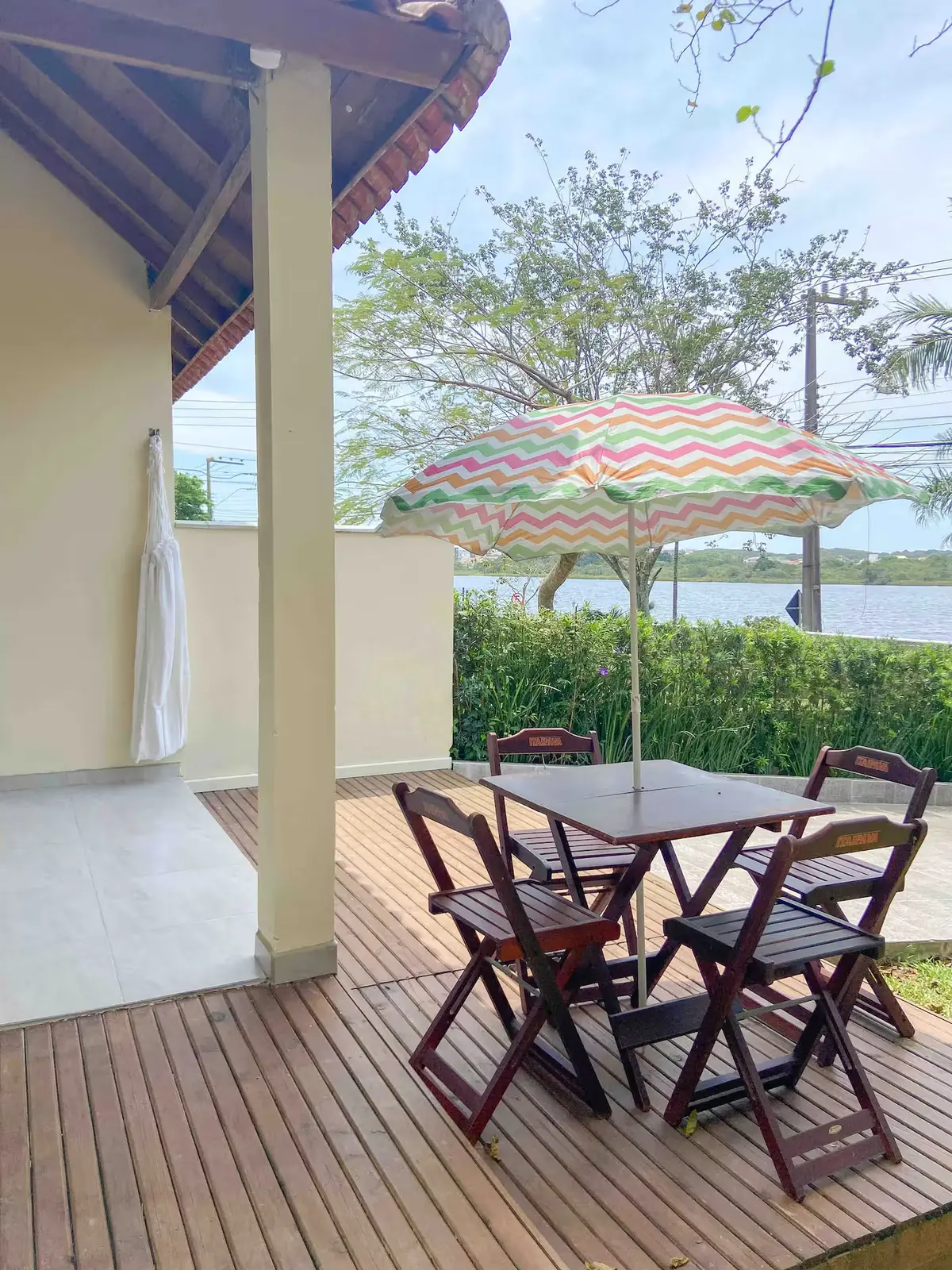 Área externa: deck com mesa e a lagoa ao fundo